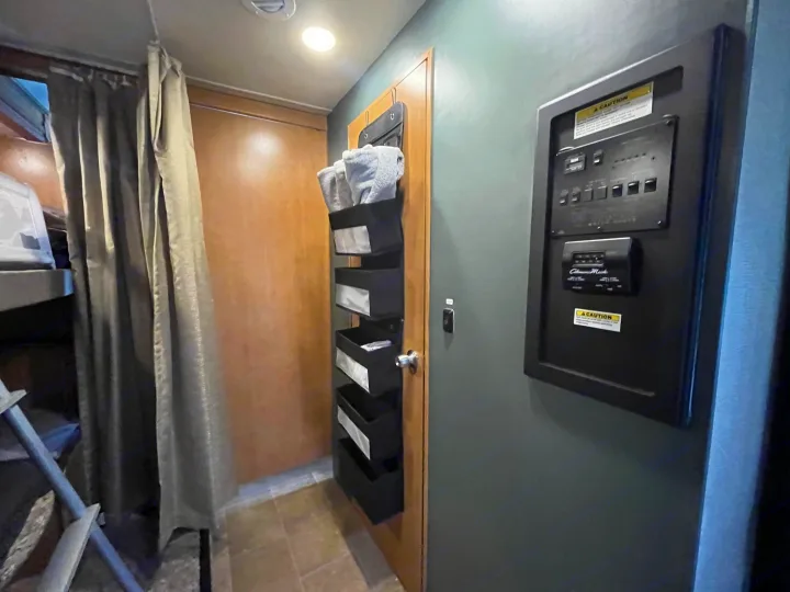 Practical RV rental interior: bunk privacy, door storage with towels, and essential system control panel.. Thor Chateau 2017