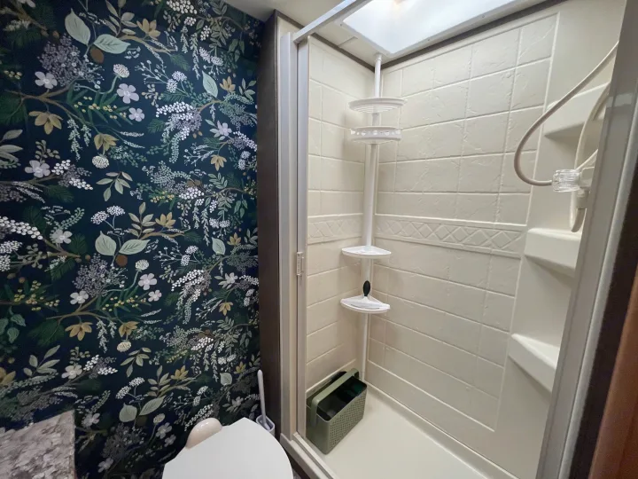 RV rental bathroom: dark floral wallpaper by the toilet, compact shower with light walls and corner shelves.. Thor Chateau 2017