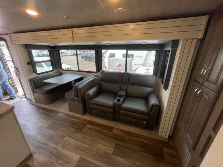 RV rental interior featuring a dining booth, recliners, and wood floors, designed for comfortable travel.. Keystone Cougar 2023