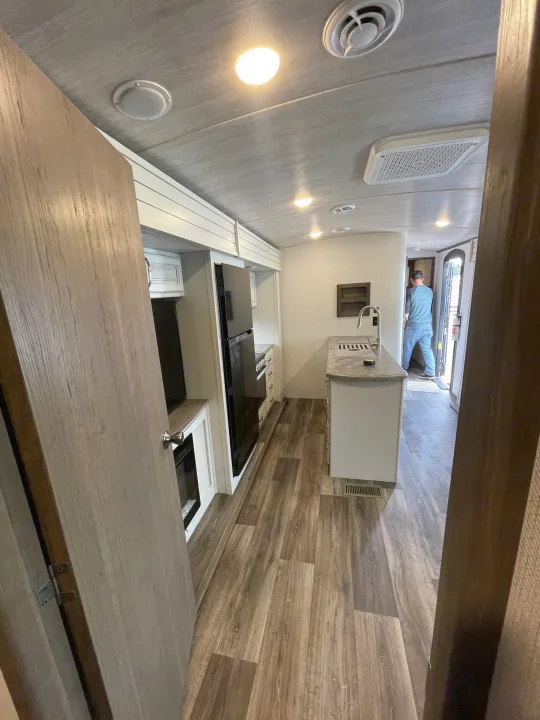 Explore this RV rental's modern interior: full kitchen with island, living space, and wood-look floors. Ready for travel.. Keystone Cougar 2023