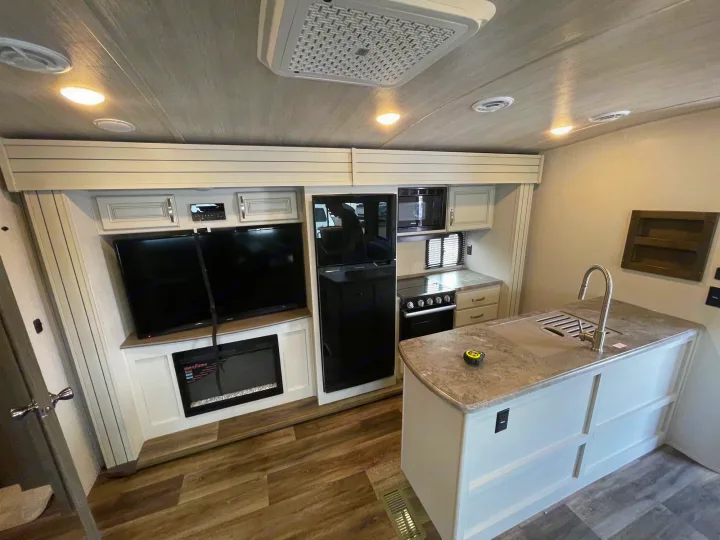 Explore this spacious RV rental interior: kitchen with island, living area with TV & fireplace.. Keystone Cougar 2023