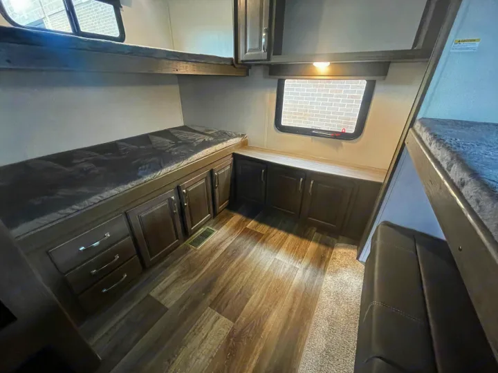 RV rental bunkhouse interior with upper & lower beds, window, ample cabinet storage, & wood-look flooring.. Keystone Cougar 2023
