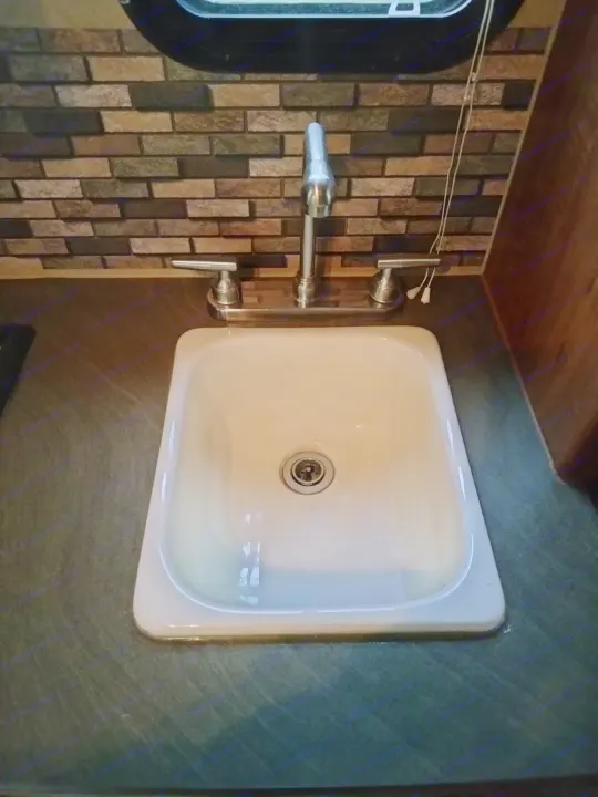 RV rental interior features a compact sink, shiny faucet, and brick backsplash on a dark countertop.. Jayco Jay Feather Ultra Lite 2013