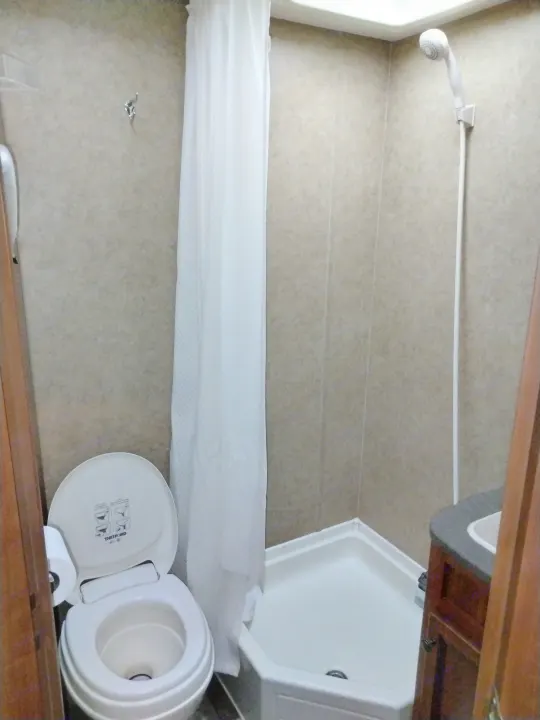Inside a compact RV rental bathroom with a toilet, corner shower stall, and small sink.. Jayco Jay Feather Ultra Lite 2013