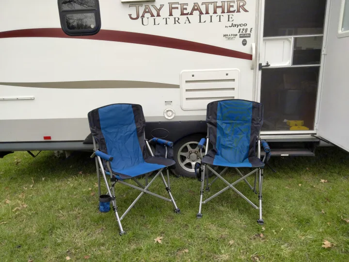 RV rental parked on grass with two blue folding chairs, ready for outdoor enjoyment.. Jayco Jay Feather Ultra Lite 2013