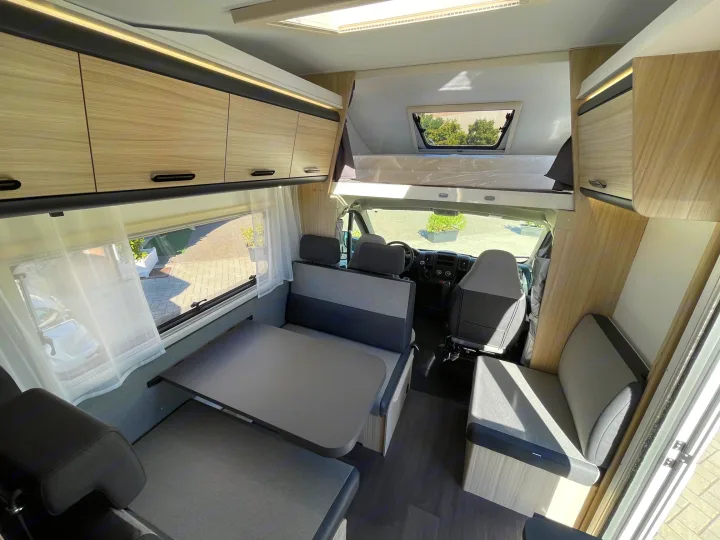 Modern RV rental interior featuring a cozy dining area, overhead bed, and ample storage. Perfect for road adventures.. SunLiving A 75 DP 23 2023
