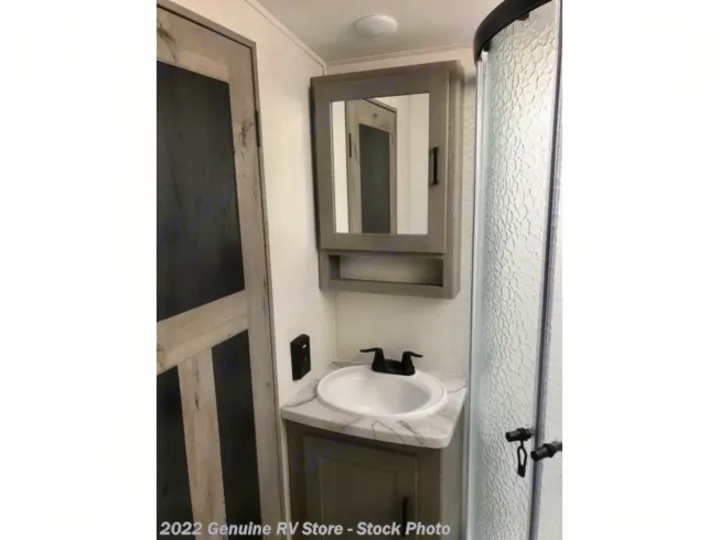 This RV rental's compact bathroom offers a corner sink, mirrored cabinet, and a curved, textured shower stall.. Keystone RV Outback Ultra-Lite 2021