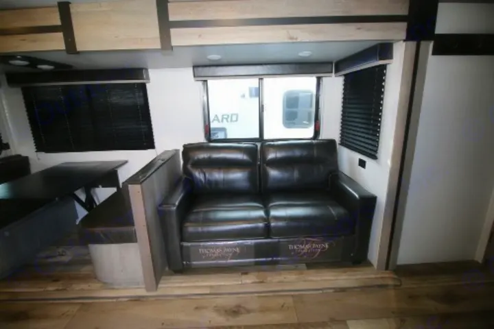 Comfortable RV rental interior: modern living space with black leather sofa and a cozy dining booth for travelers.. Keystone RV Outback Ultra-Lite 2021