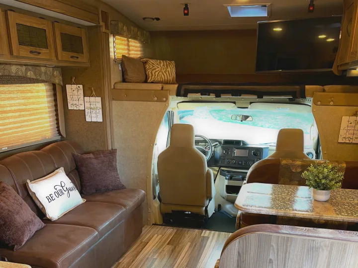 Cozy RV rental interior with sofa, dinette, overhead bunk, and cab view. Perfect for your next adventure!. Other Other 2016