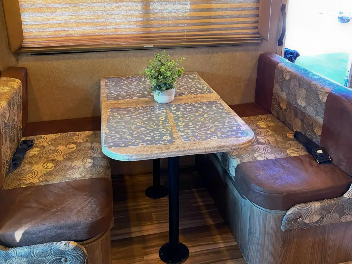Cozy RV rental interior showing a dinette with patterned booth seating, a table, and window blinds.. Other Other 2016