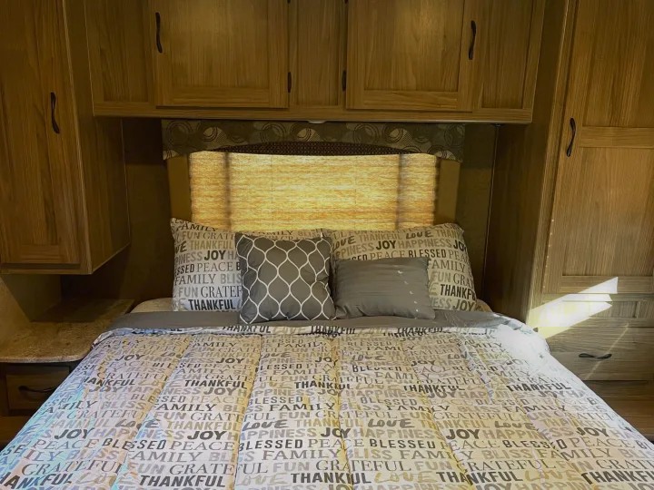 RV rental bedroom: A comfortable bed with inspirational word bedding, surrounded by warm wooden cabinetry.. Other Other 2016