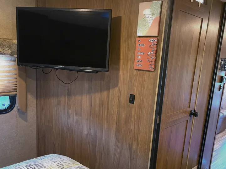 Enjoy a cozy RV rental interior featuring a mounted TV, modern wooden walls, and inspirational decor signs.. Other Other 2016