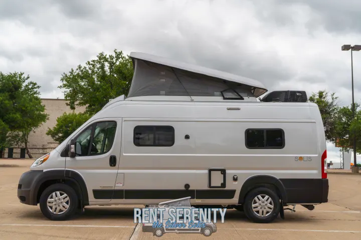 Side view of a silver Winnebago Solis pop-top camper van (RV) for rent, parked. Perfect for your next rv rental adventure!. Winnebago Solis 2023