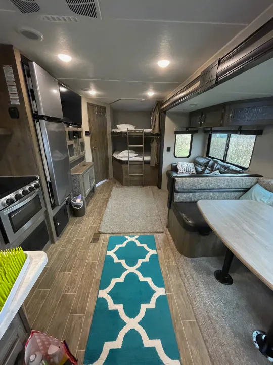 Spacious RV rental interior: well-equipped kitchen, comfy bunk beds, and dining area for travel comfort.. Forest River Palomino Puma 2019