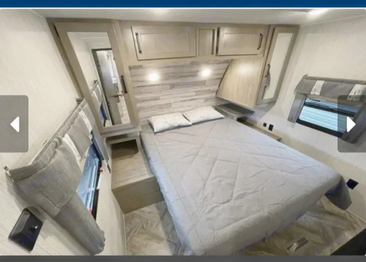Modern RV rental bedroom featuring a comfortable bed, built-in storage, and mirror. Ideal for travel comfort.. Forest River Palomino Puma 2023