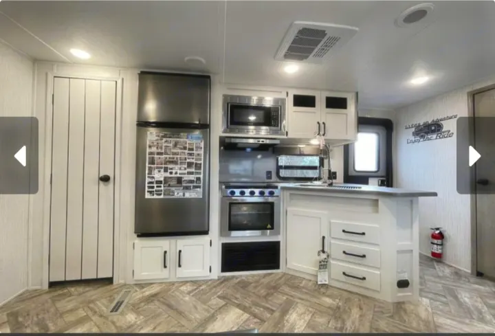 Spacious RV rental kitchen featuring modern stainless steel appliances, white cabinets, and bright interior.. Forest River Palomino Puma 2023