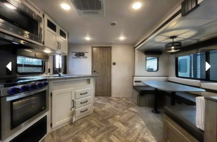 Spacious RV rental interior featuring a modern kitchen with oven/microwave and a comfy U-shaped dining area.. Forest River Palomino Puma 2023