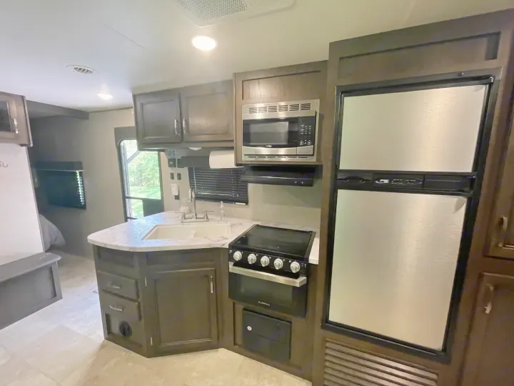 Spacious RV rental interior featuring a full kitchen with microwave, stove, fridge, and ample cabinets. Ideal for travel.. Jayco Jay Flight SLX 2021