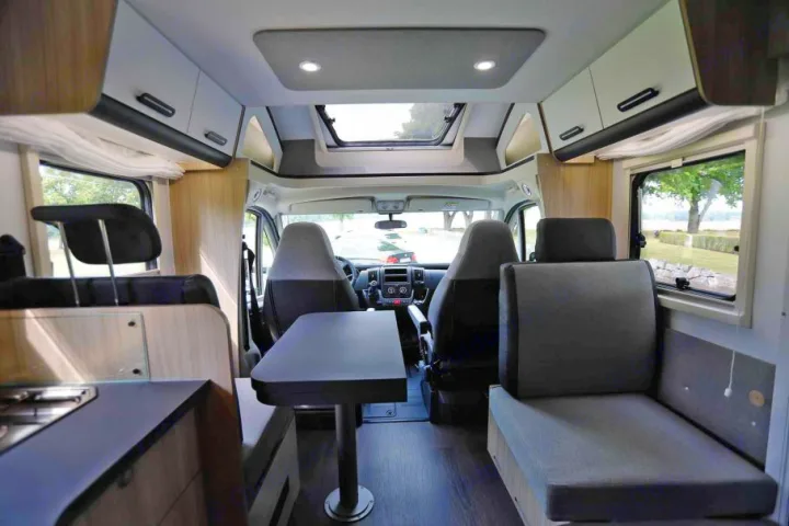 Modern rv rental camper van interior: bright cab, dining area, kitchen, and skylights for scenic views.. SunLiving S 72 DL 2023