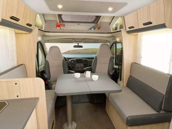 Explore this modern rv rental interior, featuring a dining area, comfortable seating, and a scenic ocean view from the cockpit.. SunLiving S 72 DL 2023