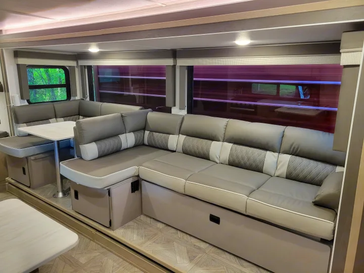 Modern gray U-shaped dinette and lounge with a table inside an RV rental. Features comfortable seating and large windows.. Forest River 31bhxl 2023