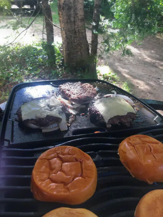 Grilling tasty burgers with melting cheese and buns outdoors, great for an RV rental trip!. Other Other 2019