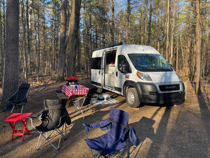 Enjoy your RV rental adventure! Camper van parked at a wooded campsite with picnic table, grill, and chairs set up for outdoor fun.. Other Other 2019