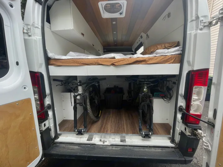 RV rental camper van interior: elevated bed above secure bike storage for two mountain bikes. Features wood ceiling.. Other Other 2019