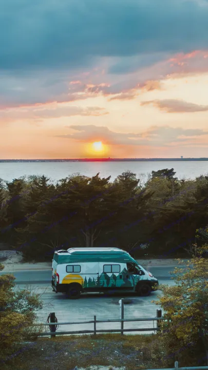 RV rental: A custom camper van with mountain graphics, parked at a scenic sunset by a calm bay.. Winnebago Solis 2022