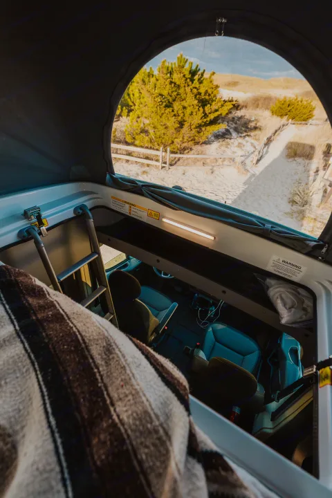 Cozy RV rental interior with pop-top roof open to beach views. Perfect for road trip adventures!. Winnebago Solis 2022