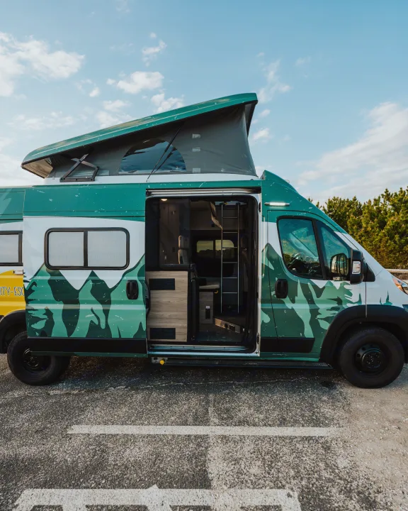 Green & white pop-top camper van with open side door. Ready for adventure with this spacious RV rental.. Winnebago Solis 2022