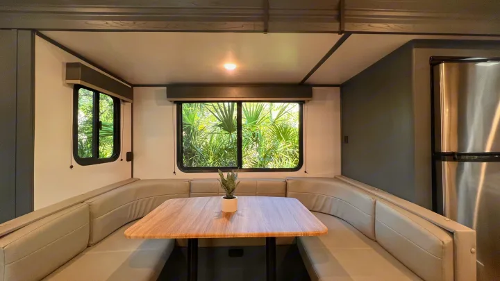 Spacious rv rental dinette with U-shaped seating, wood table, and views of palms.. Keystone RV Bullet Ultra Lite 2022