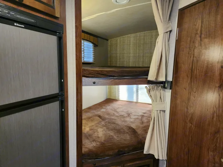 RV rental interior: Cozy bunk beds with privacy curtains, window, and a Dometic refrigerator.. Cruiser RV MPG Ultra Lite 2017