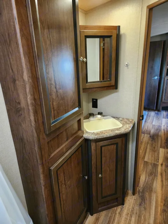 Compact RV rental bathroom with a dark wood vanity, sink, mirrored medicine cabinet, and tall storage.. Cruiser RV MPG Ultra Lite 2017