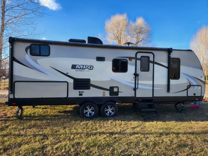 An MPG Ultra-Lite travel trailer, ideal for an RV rental, is parked on grass on a sunny day. Stability jacks are down.. Cruiser RV MPG Ultra Lite 2017