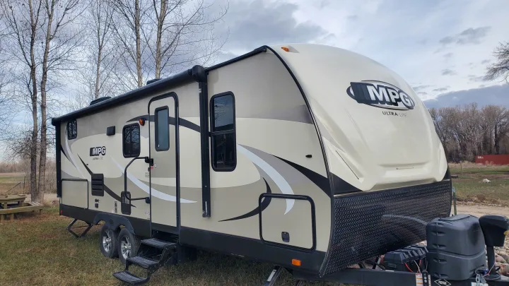This beige MPG Ultra-Lite travel trailer, perfect for an RV rental getaway, is nestled in a natural, open landscape.. Cruiser RV MPG Ultra Lite 2017