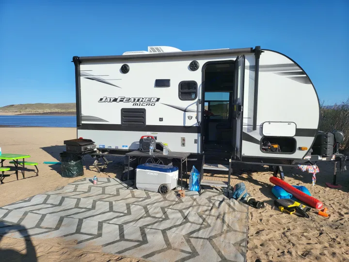 Experience beach camping with this RV rental! Features an outdoor kitchen, cooler, and mat by a scenic lake.. Jayco Jay Feather Micro 2022