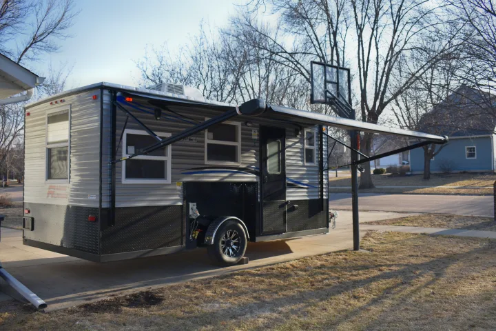 RV rental: Spacious grey camper trailer with extended awning, parked on a residential driveway.. Ice Castle Fish Houses Rv Edition Standard 2024