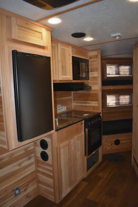 RV rental interior showcasing a full kitchen with a fridge, stove, sink, and warm wood finishes.. Ice Castle Fish Houses Rv Edition Standard 2024