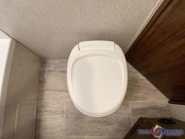Top-down view of a clean, white RV toilet in a compact bathroom, ideal for your next RV rental adventure.. Heartland RVs Mallard 2019