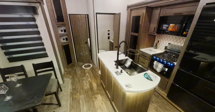Explore this modern RV rental interior: a spacious kitchen with island, dining area, and accessible bathroom.. Forest River Sabre 2022