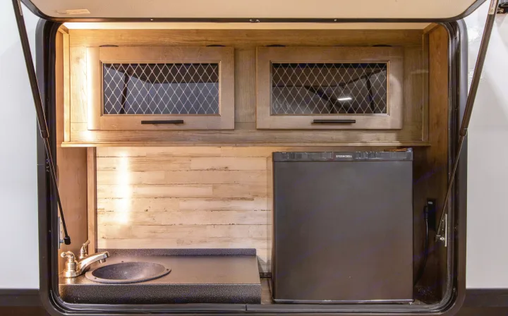 This RV rental features an outdoor kitchen: sink, faucet, fridge, and cabinets. Perfect for camping convenience.. Forest River Sabre 2022