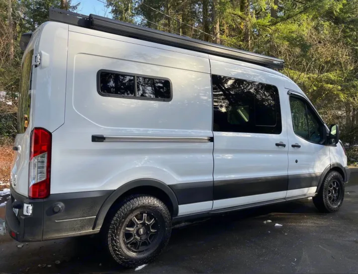 Explore with this white custom Ford Transit camper van RV rental. Features off-road tires & roof awning for adventure.. Ford Transit 2019