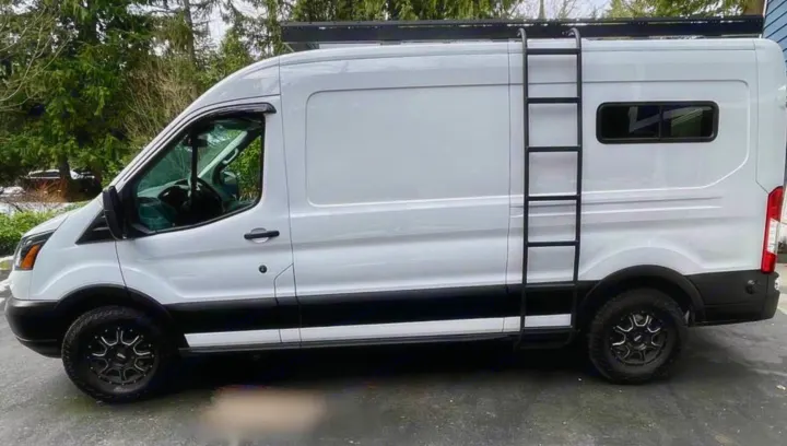 White Ford Transit camper van for **rv rental**, featuring a roof rack, ladder, and rugged tires for off-road adventures.. Ford Transit 2019