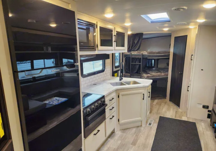 Spacious RV interior with kitchen, bunk beds, and lounge area. Perfect for your next RV rental adventure.. Jayco Whitehawk 2023