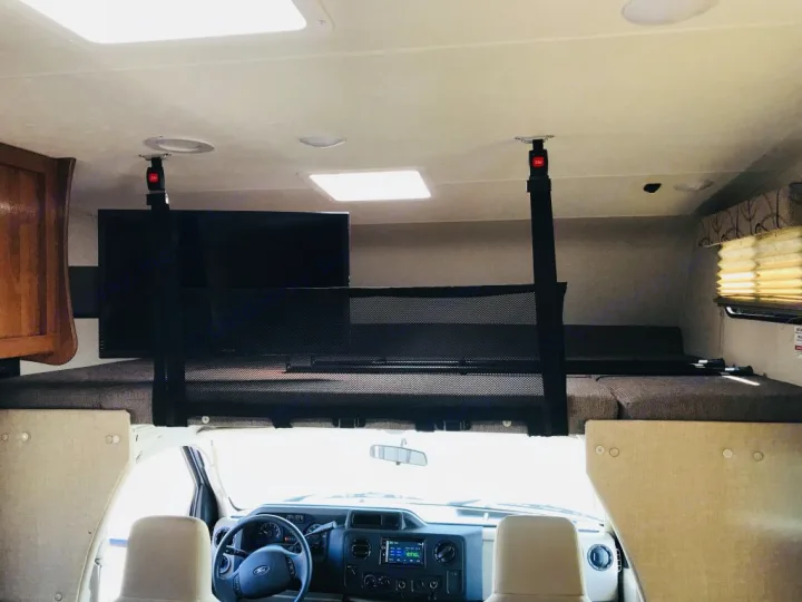Experience comfort in this RV rental: overhead bunk bed with safety net, TV, and front cab view.. Coachmen Leprechaun 2016