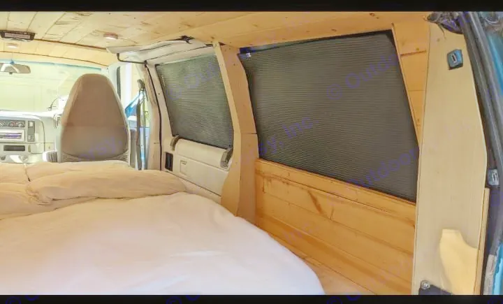 Inside this cozy RV rental: a wood-paneled camper van conversion with a comfortable bed & window blinds.. Chevrolet Other 1996