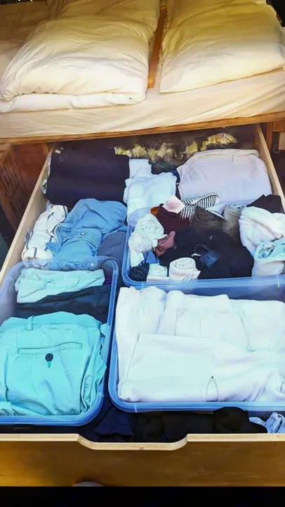 Under-bed storage in an RV rental, showing neatly organized clothes packed in clear plastic bins within a wooden drawer.. Chevrolet Other 1996
