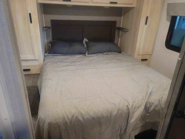 Cozy RV rental bedroom with a large bed, built-in side cabinets, and overhead storage for a great trip.. Forester LE 2022