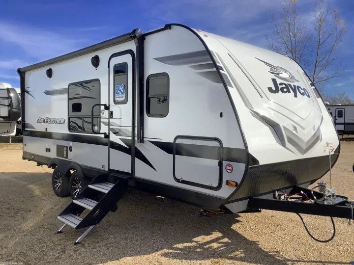 Pristine white Jayco Feather travel trailer, ideal for your next RV rental. Parked on gravel with steps extended.. Jayco 21MML 2023